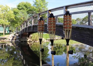 Set of three bamboo torches next to river with bridge