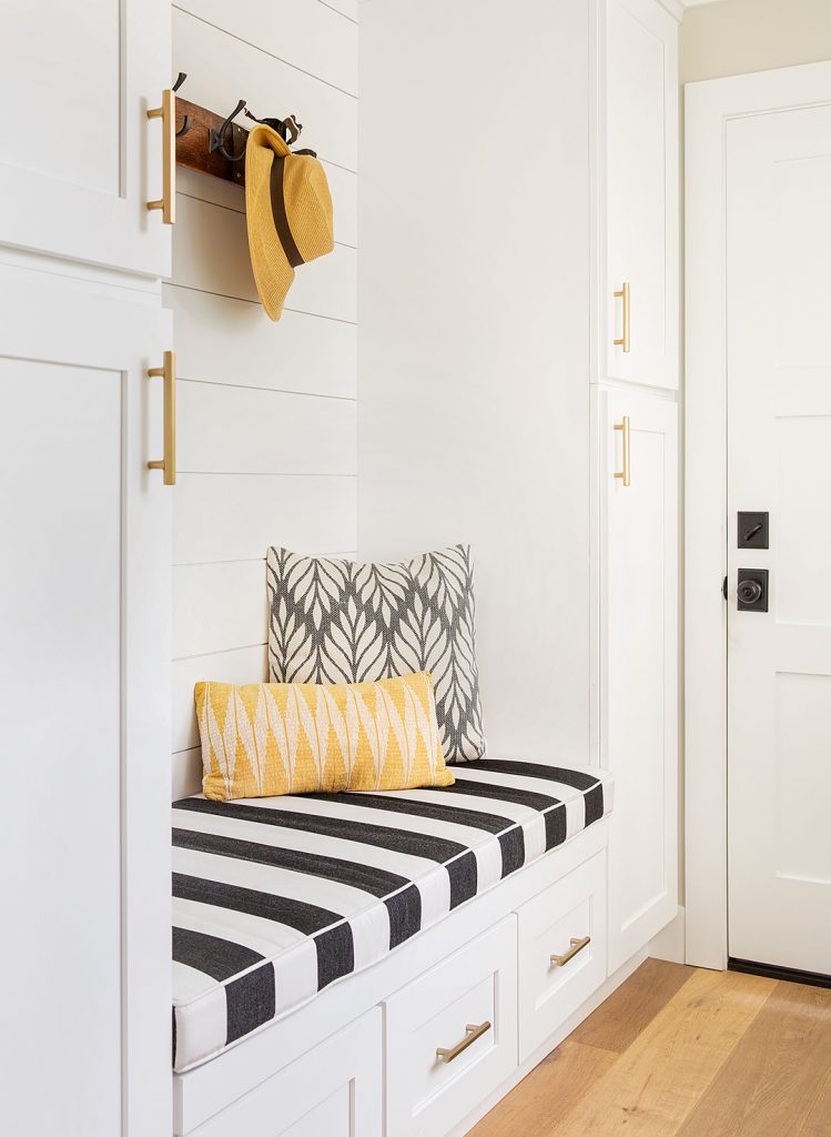 Laundry and mudroom design ideas: mudroom area with shiplap walls, a striped built in bench cushion and modern floral pillows