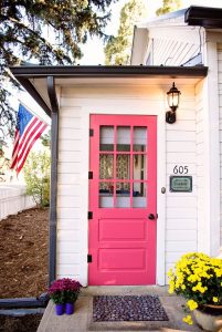 Red side door with American flag hanging above home