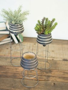 Industrialized Modern Black_Clay_Planters_With_Metal_Stands planted with succulents on a worn wooden tabletop