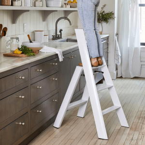 Woman standing on step ladder in kitchen