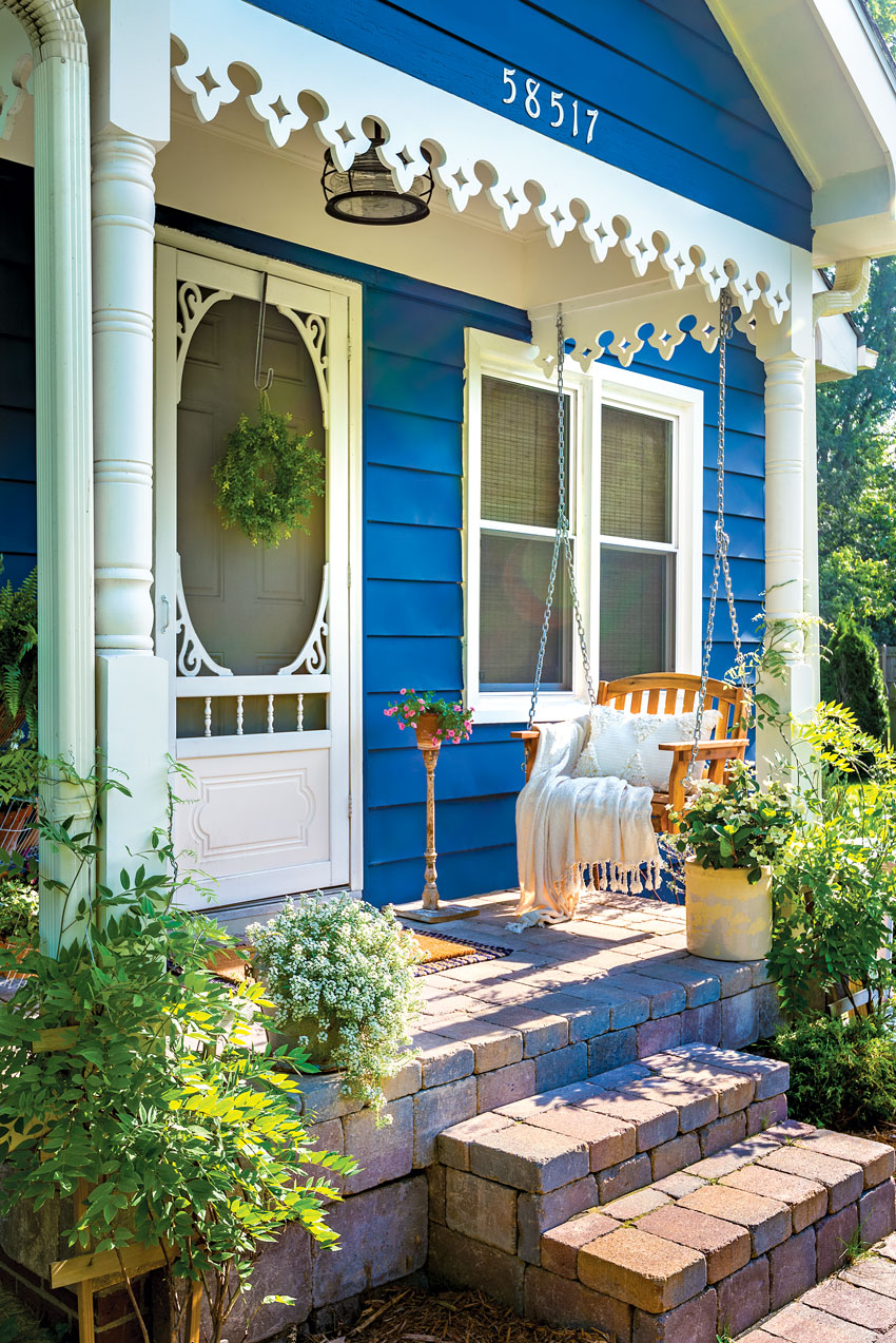 Porch swing on small front porch of blue and white country cottage 