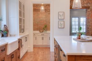 Kitchen with reclaimed brick accent walls, white countertops and wood floors