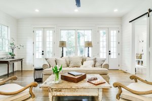 Living room with white shiplap walls, a vintage coffee table and neutral furniture.