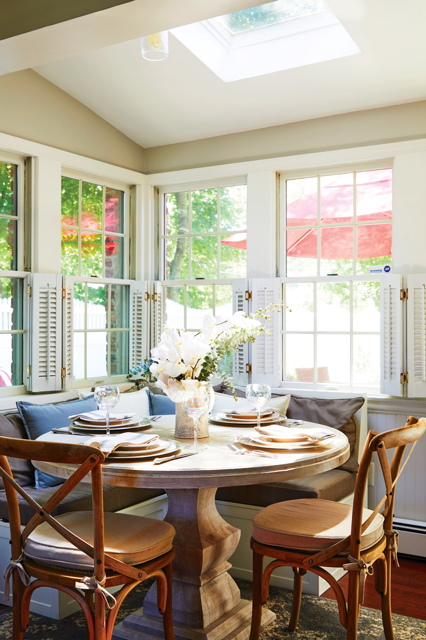 sunny view of dining nook with round table, two chairs and bench seating