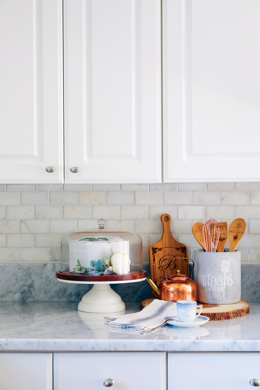 white kitchen counter iwth vignette of wooden and copper tools and accessories 