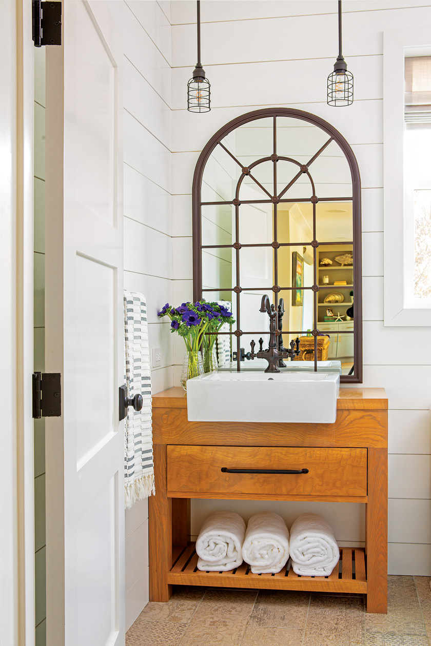 guest bathroom with natural wood vanity, white square sink, arched mirror above and two pendant lights above