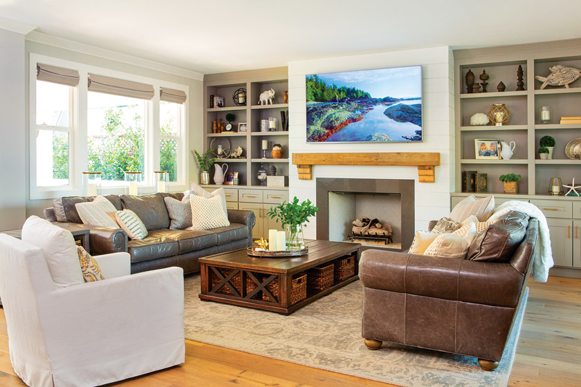 living room with open shelving, large television, white chair, leather sofa and fireplace 