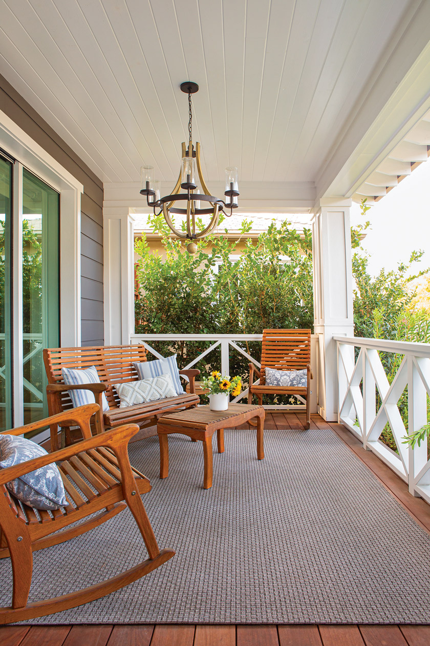 white coastal farmhouse with open porch with teak furniture set and chandelier from ceiling