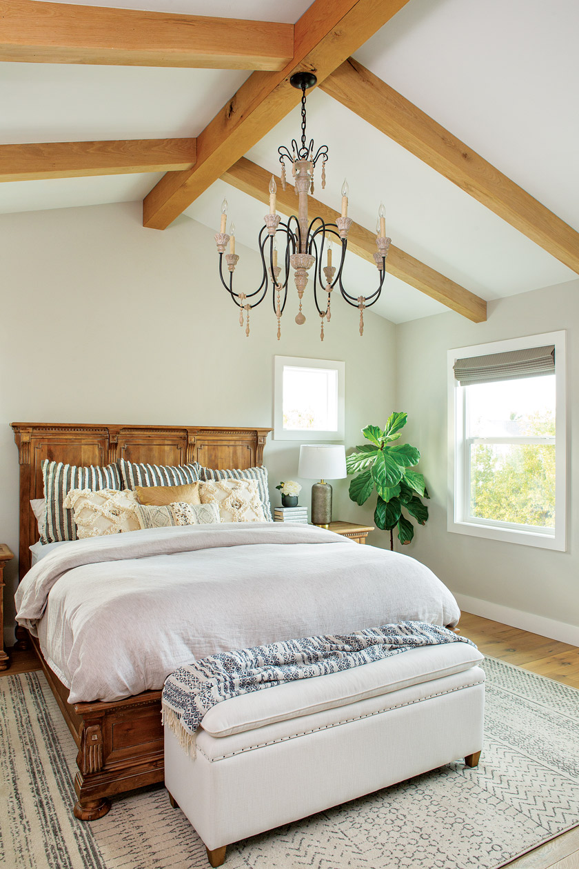 white master bedroom with large chandelier and natural farmhouse wood open beams