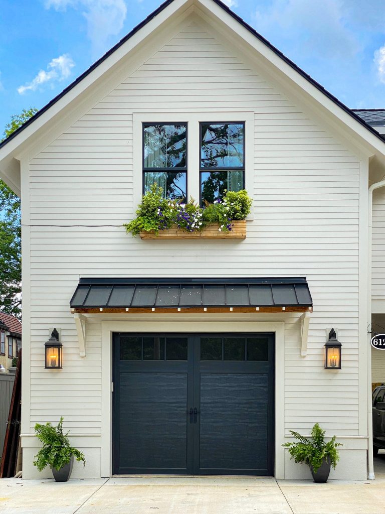 The garage door catches your eye with its pop of dark charcoal against the white siding. 