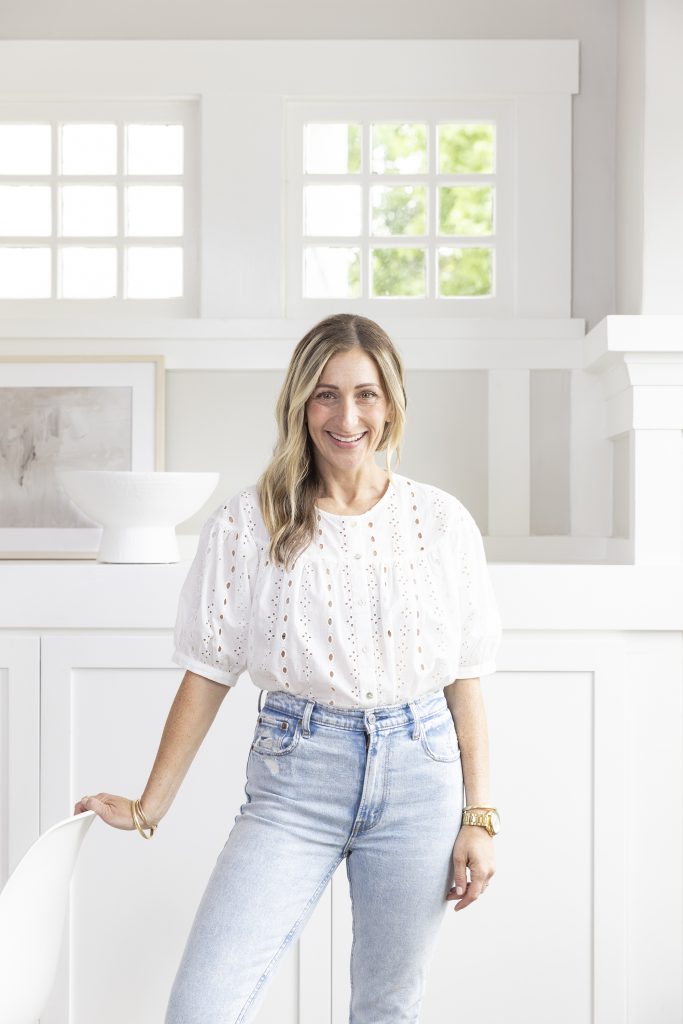 Shira Gill rests her hand on a chair and smiles at the camera