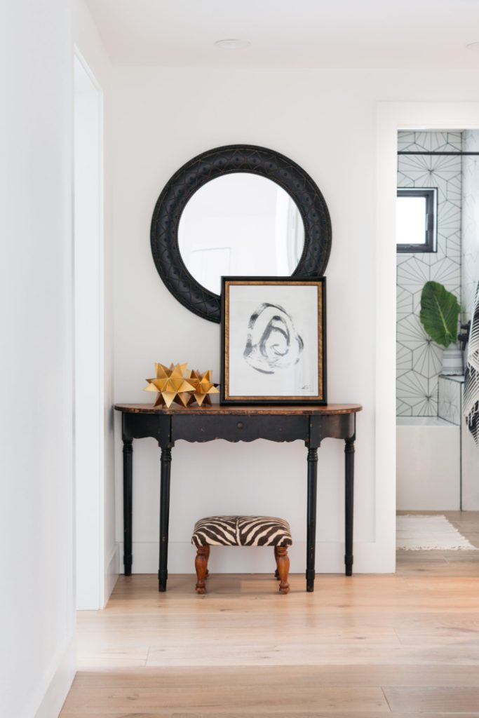 Hallway with side table and black circular mirror, along with abstract art details