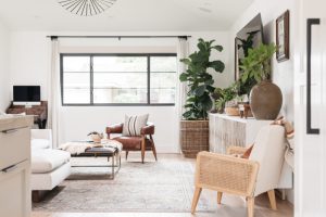 Black and tan living room with leather seating and greenery in modern beach home