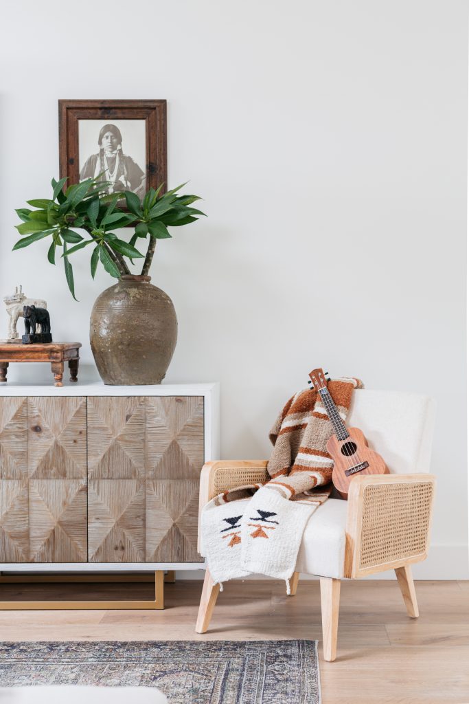 Striped blanket and ukulele on top of a woven chair with white cushion