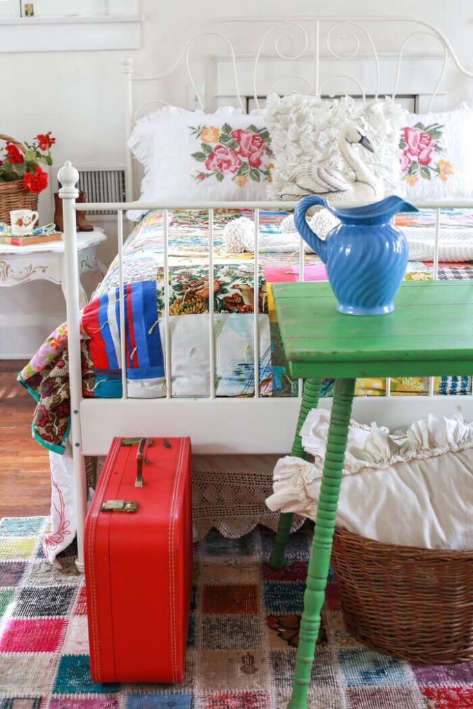 A vintage red suitcase standing at the foot of a bed