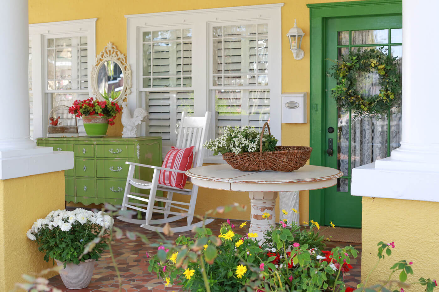 Front porch featuring a table, rocking chair, pillow, buffet table, mirror, and flowers