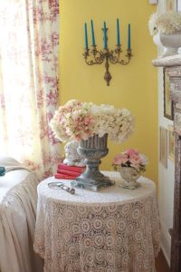 Flowers in a vase on top of a table covered in a vintage tablecloth