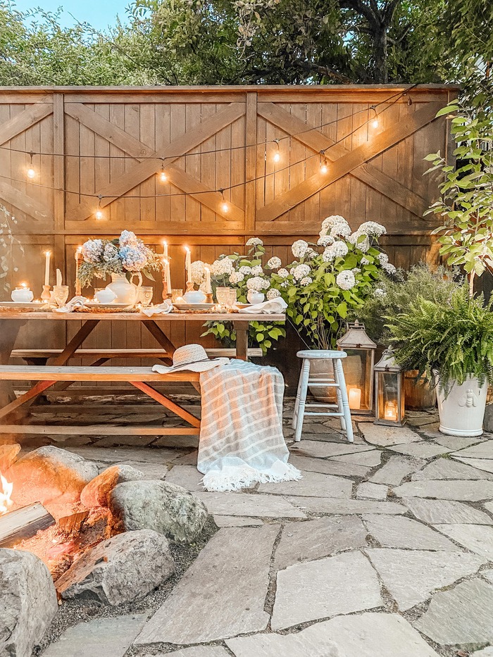 Outdoor patio with picnic table decorated with candles and string lights