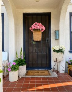 Pink flowers in a basket hanging on a black front door