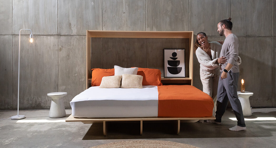 A man and woman stand at the edge of the folded-out Lori Murphy bed.