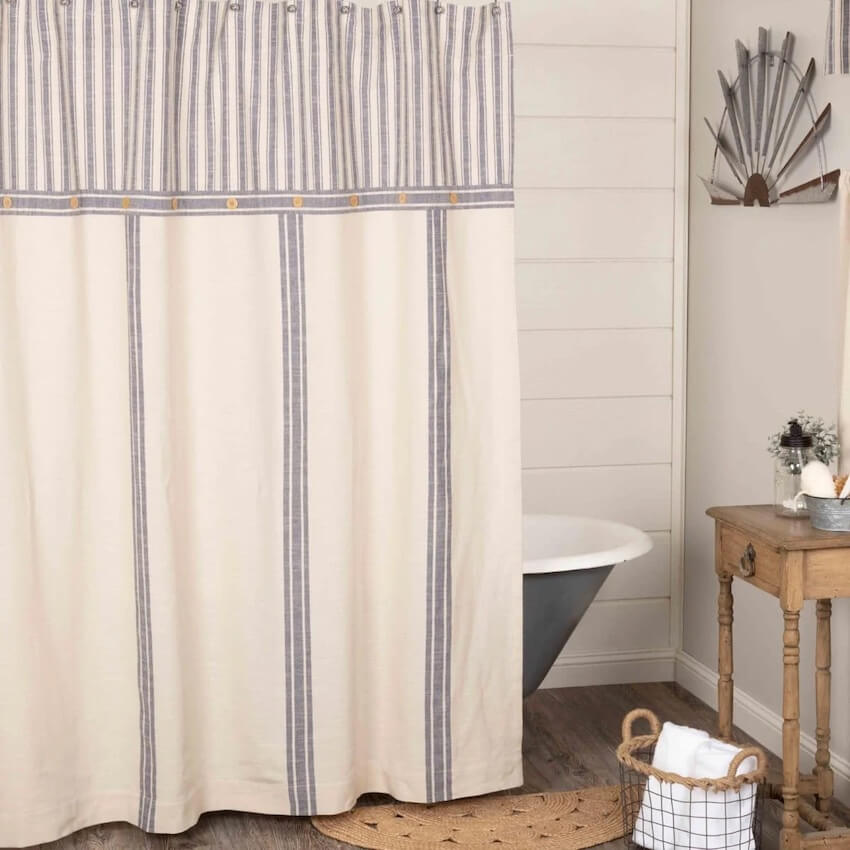 A blue and white striped shower curtain partly conceals a blue freestanding bathtub