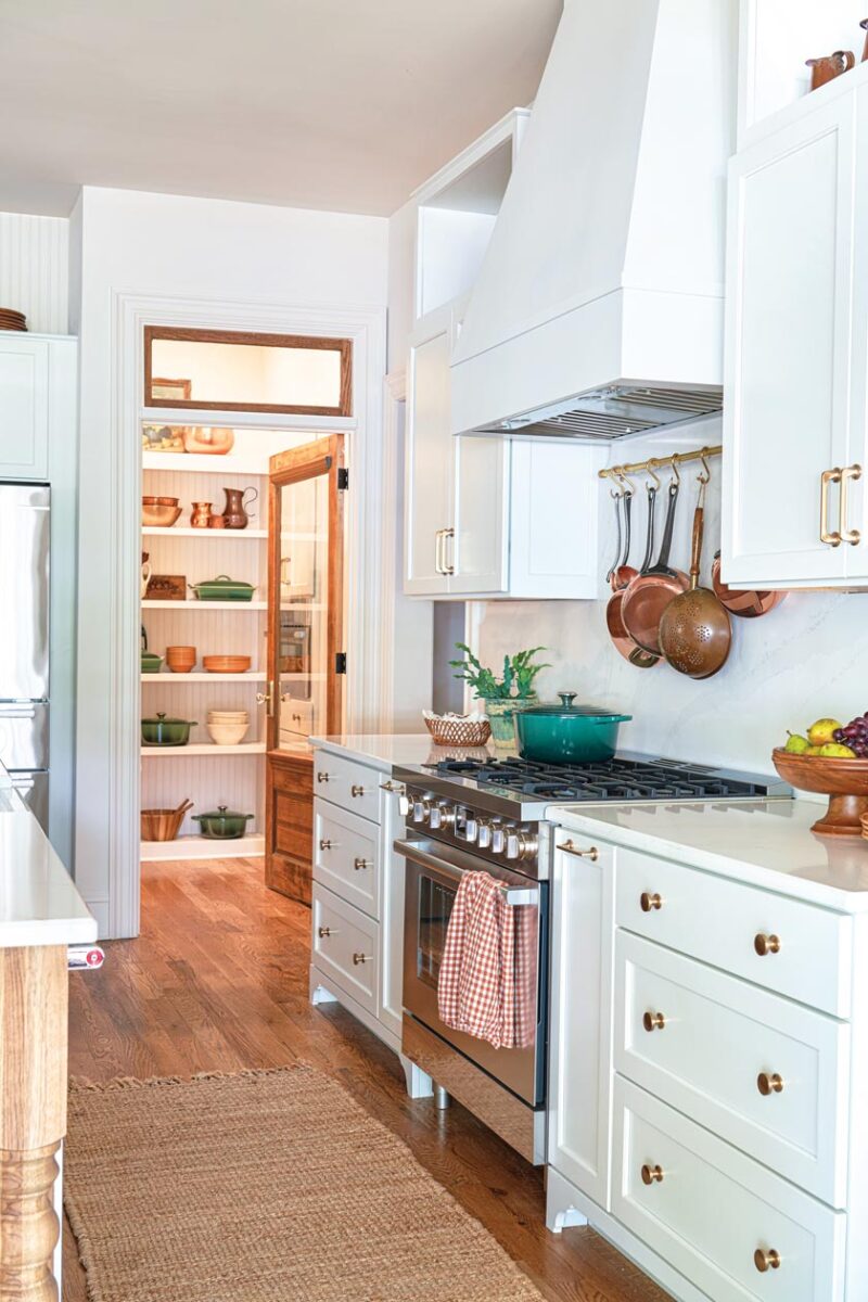 kitchen with hanging pots and white oven hood