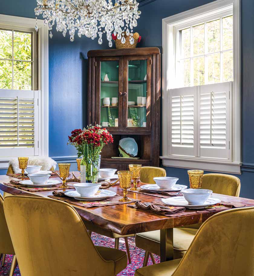 blue dining room with gold chairs and amber vintage glasses and chandelier