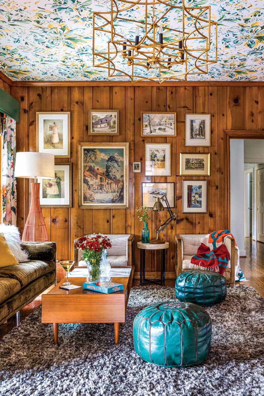 floral patterned ceiling and teal poufs and gallery wall in wood paneled room of historic Nashville home