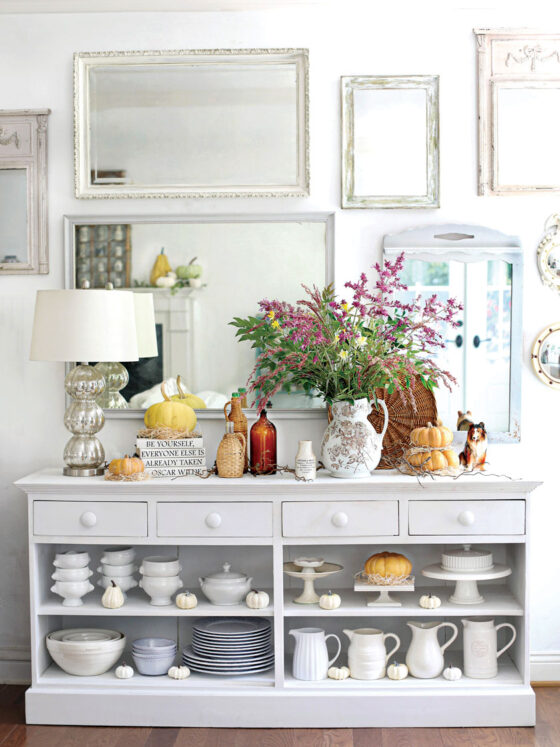 sideboard styled with white dish ware and pumpkins