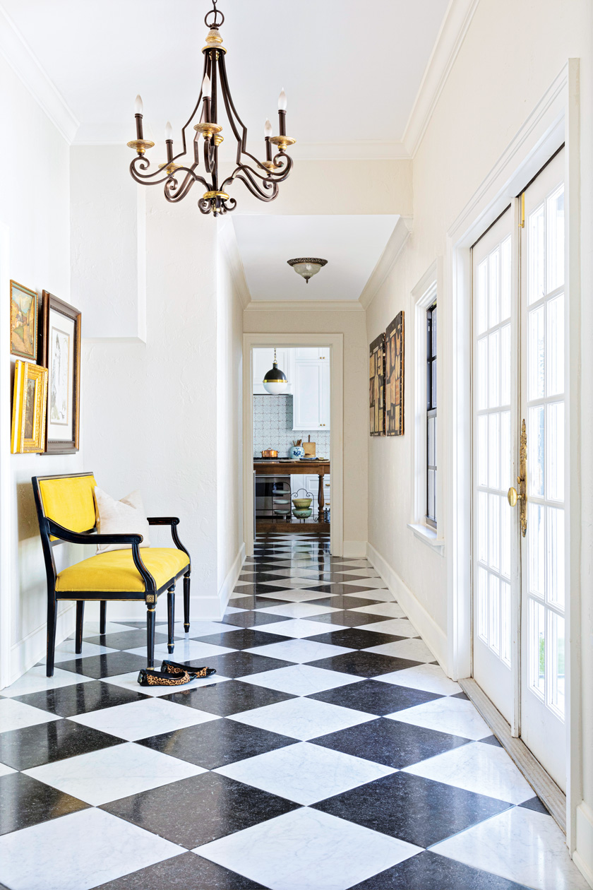 checkered floor and wrought iron chandelier and yellow accent chair in hallway leading to kitchen