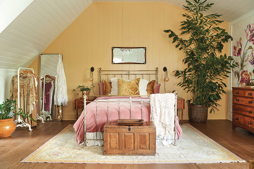 bedroom with yellow beadboard iron bed and floral wallpaper accent wall