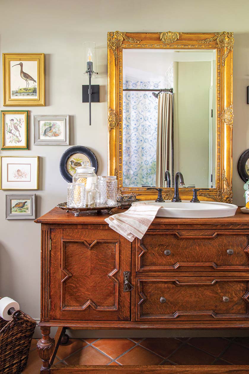 sink in repurposed vintage dresser and gallery wall of bird art in bathroom of renovated California home