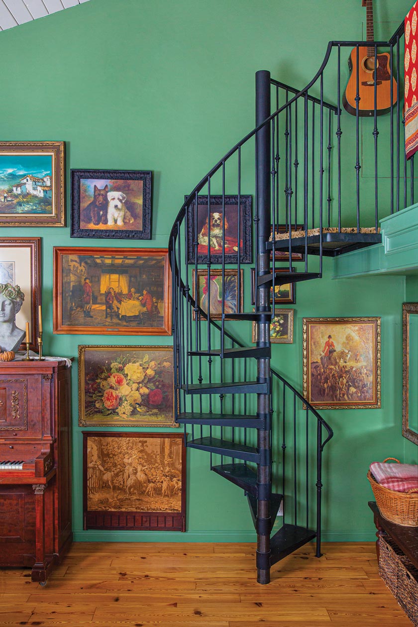spiral staircase and gallery wall painted green in maximum style cottage
