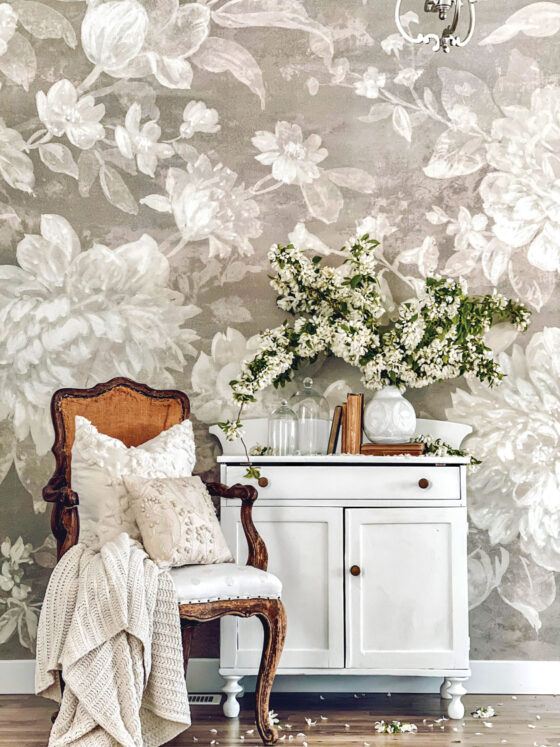 small space decorated with statement wallpaper, white cabinet, vintage books and armchair