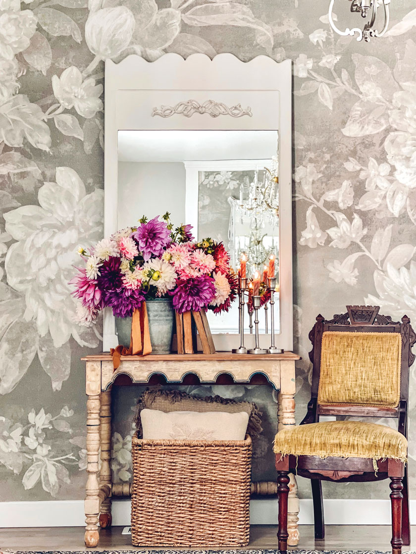 statement floral wallpaper with vintage mirror and cabinet and armchair