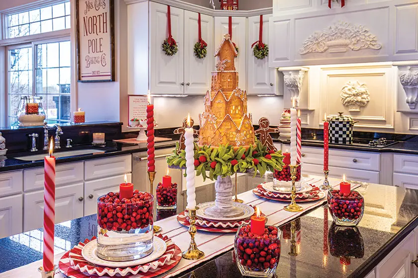 gingerbread castle and candles in votives filled with cranberries in holiday kitchen