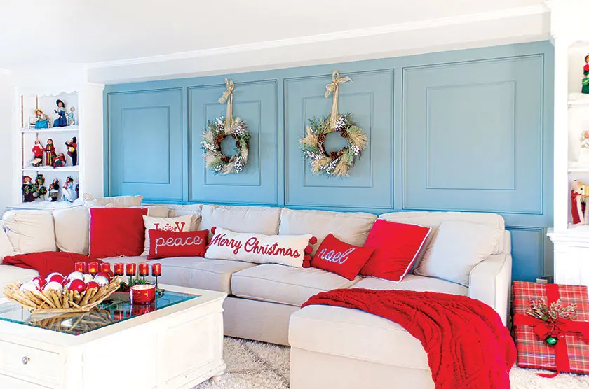 blue accent wall in family room and couch with red holiday throw pillows