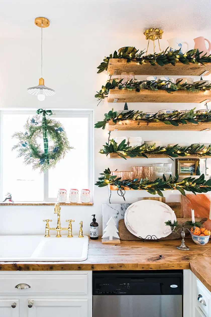 lights and magnolia leaves decorating exposed kitchen shelving