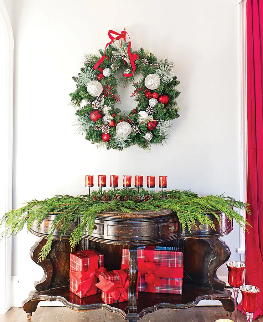 holiday wreath and cedar on console table with red candlabra