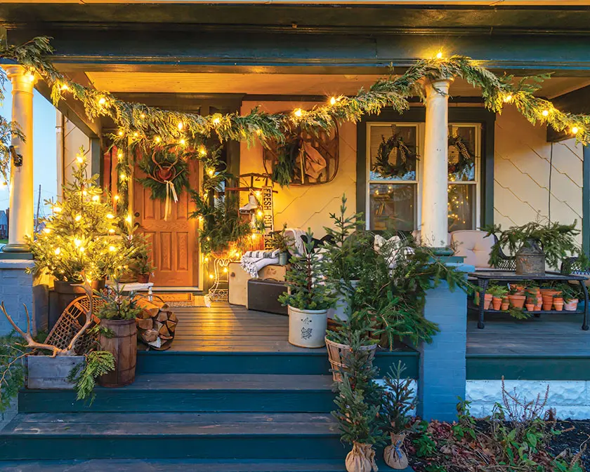 exterior of cozy holiday home with fresh garland and potted evergreens