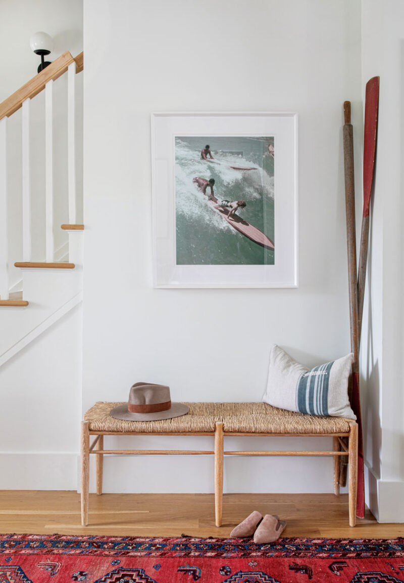 surfing photo and woven bench in entryway of sophisticated beach bungalow