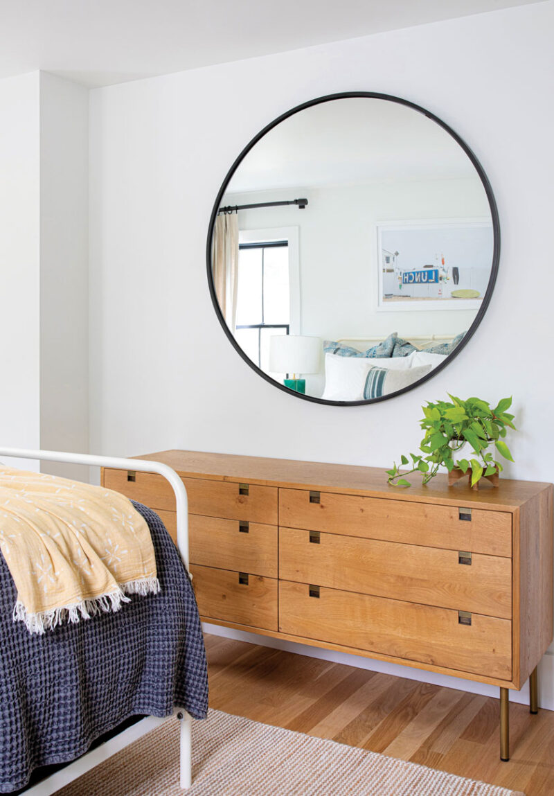 circular mirror in bedroom with wooden dresser