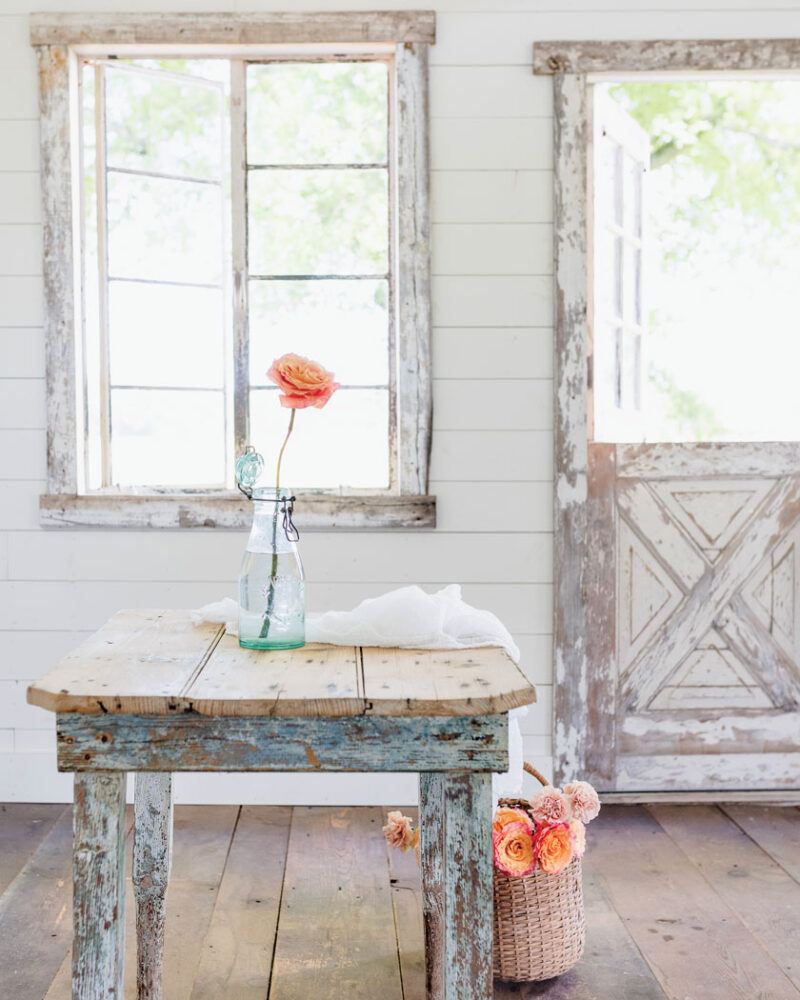 chippy white paint and peach roses in vintage style bottle as vase