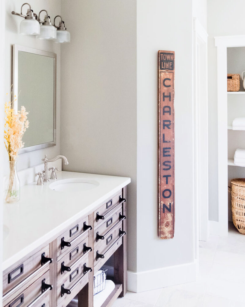 white flower arrangement in bathroom with vintage sign as wall decor