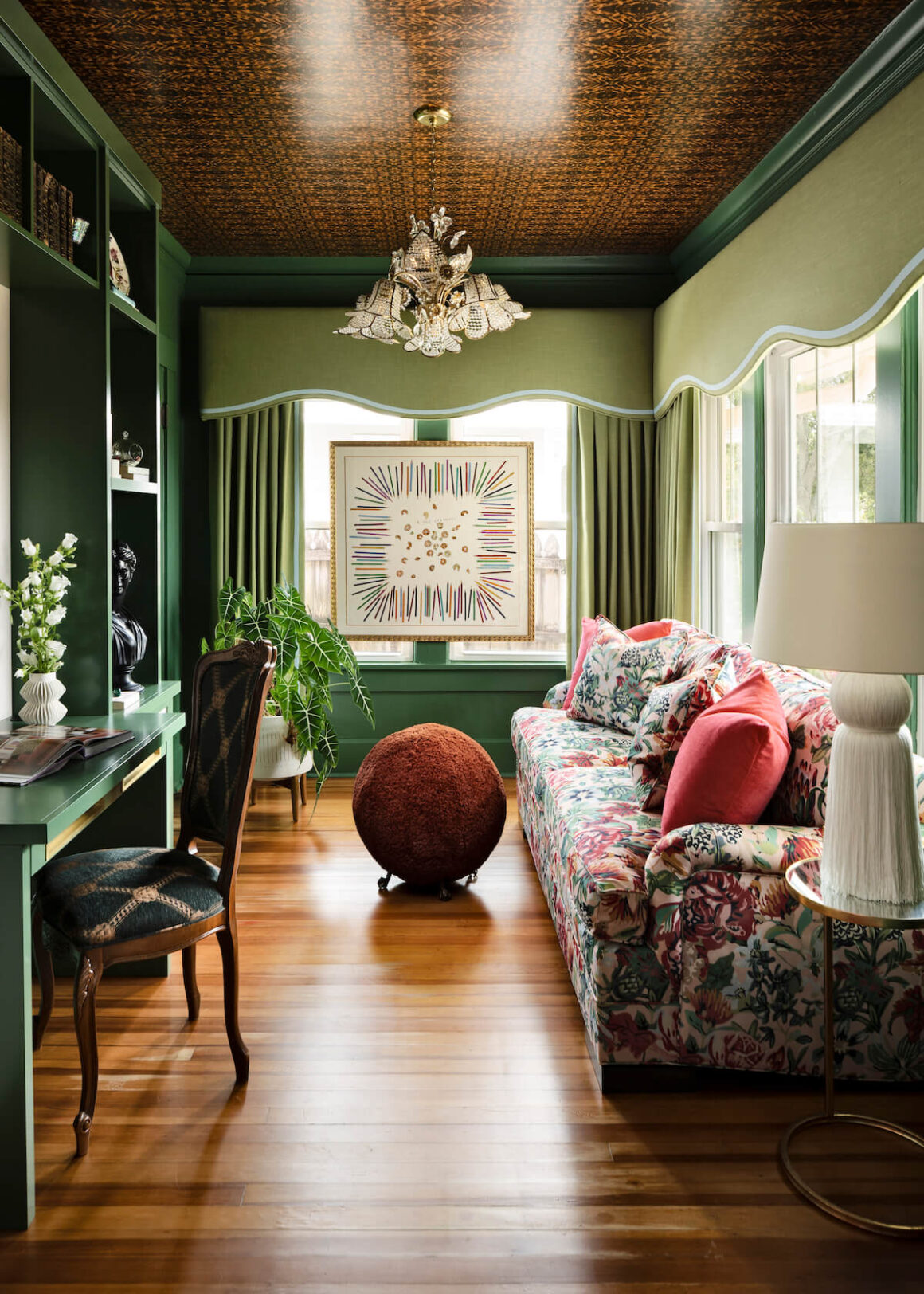 study with floral patterned couch and green walls and window treatments