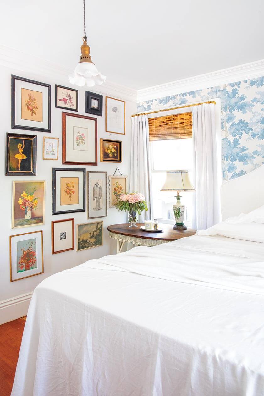 small cottage styling in bedroom with gallery wall and white and blue color scheme