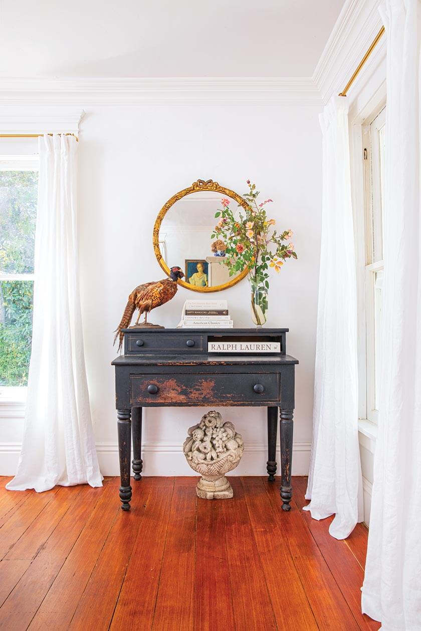 vintage desk and bird figurine in small white cottage