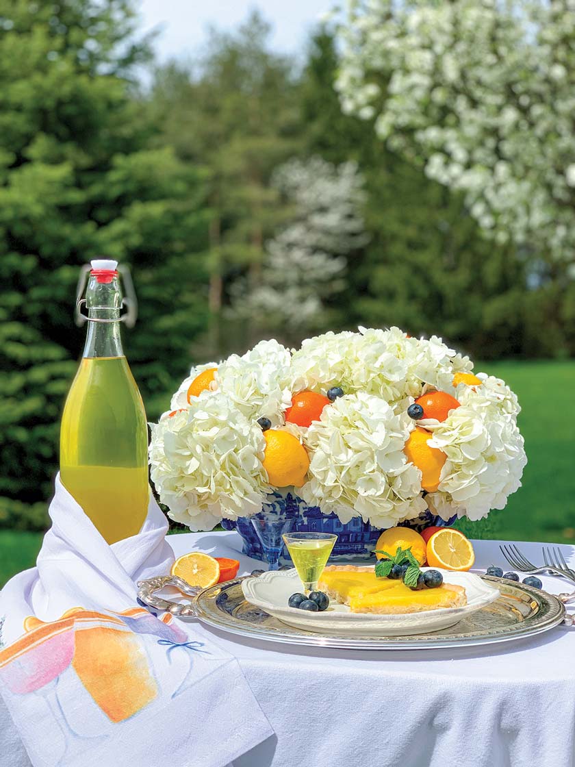 outdoor summer tablescape with fruit layered into bouquet of hydrangeas