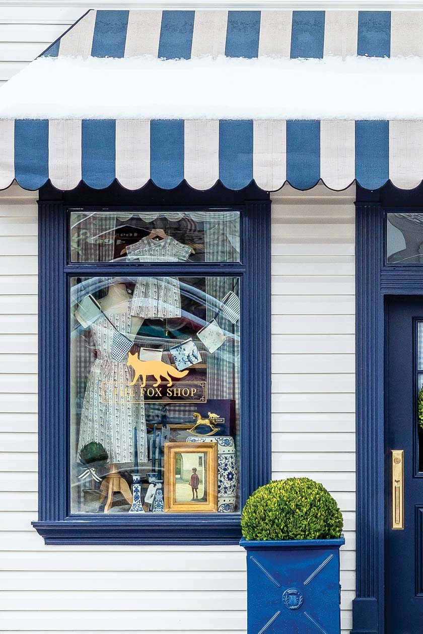 The Fox Shop storefront with blue and white awning and blue trim and door
